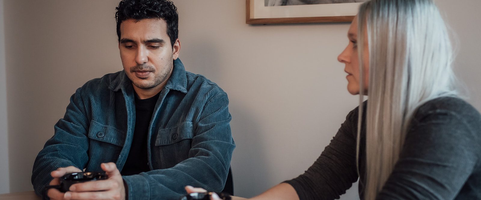 A man and woman sitting at a table holding coffee mugs having a serious conversation.