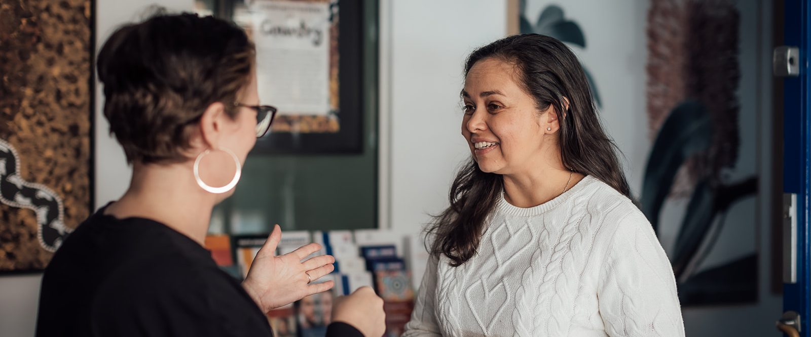 Two women talking and smiling in a reception area.