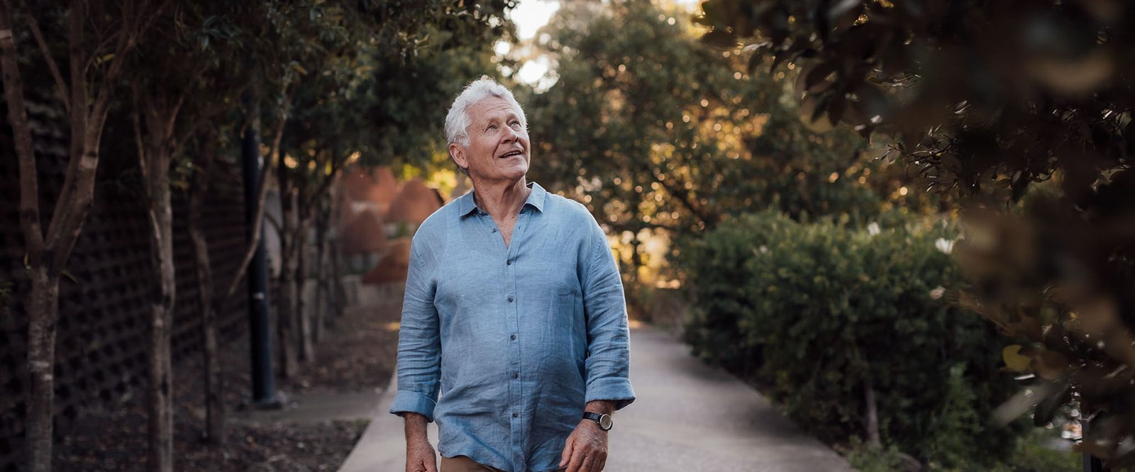 An older man walking on a path, enjoying nature.