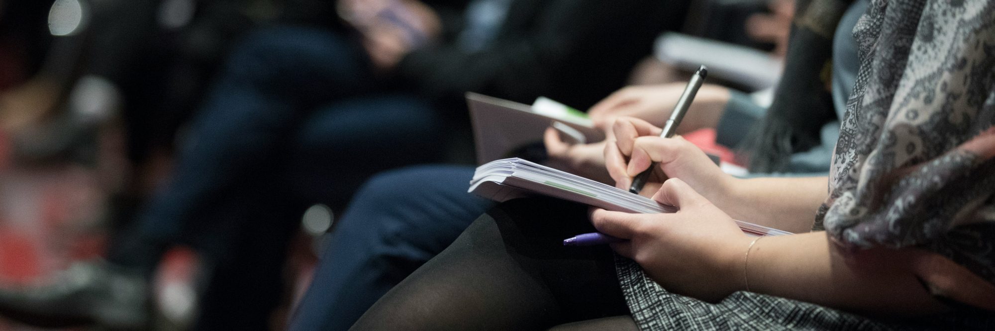 People sitting in a row taking notes.